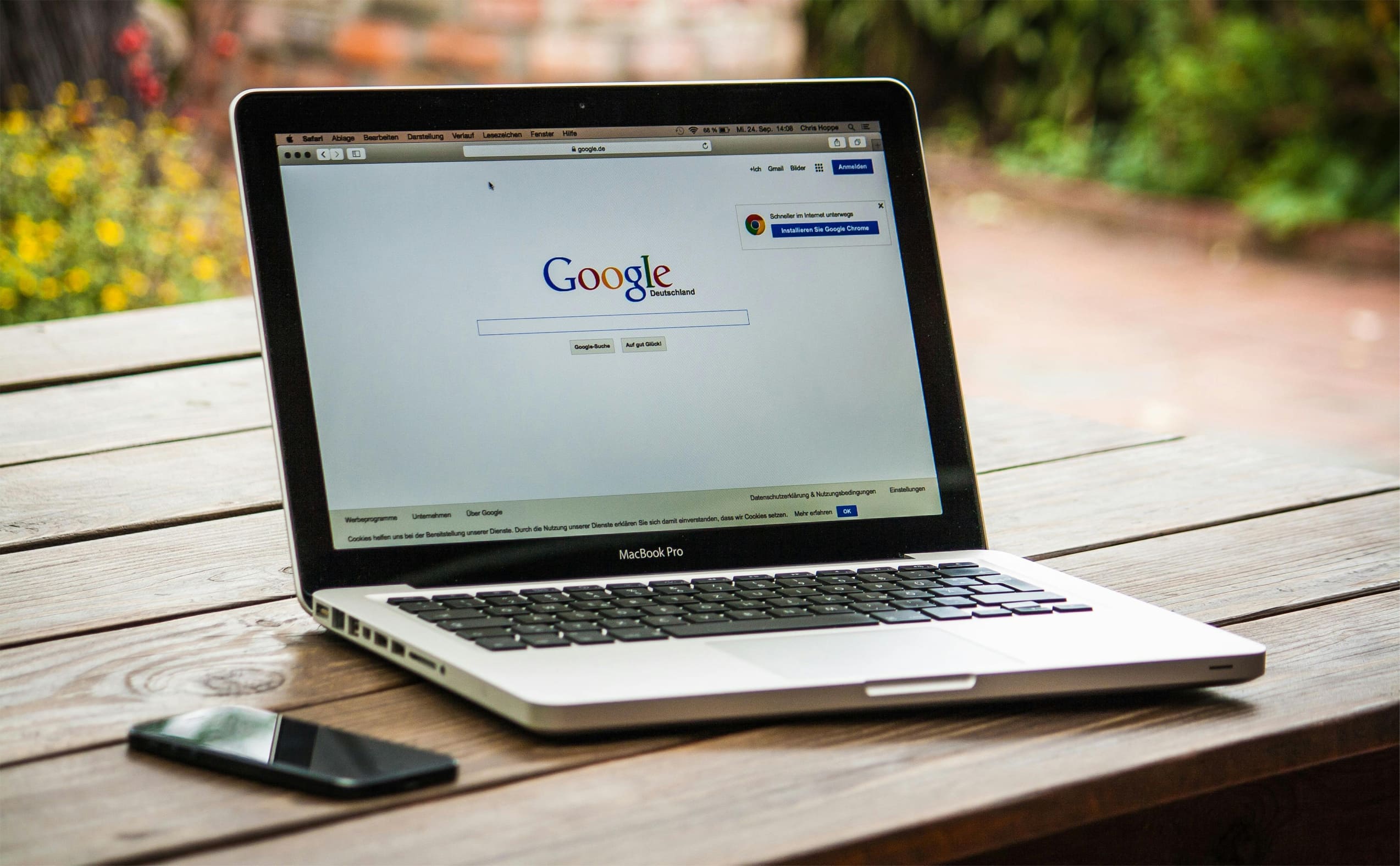Ordinateur portable sur une table en bois affichant la page de Google, illustrant les recherches d’un client pour trouver un contenu optimisé.